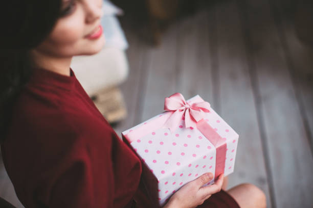 istock Gift with pink ribbon in female hands. Top view. 678016084