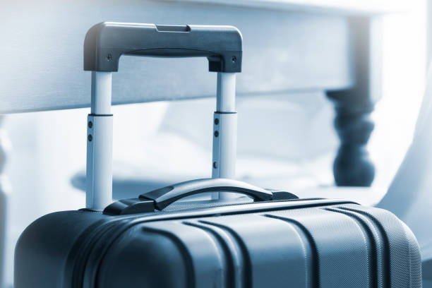 istock Close up of a modern, black, wheeled suitcase beside a table 678026026
