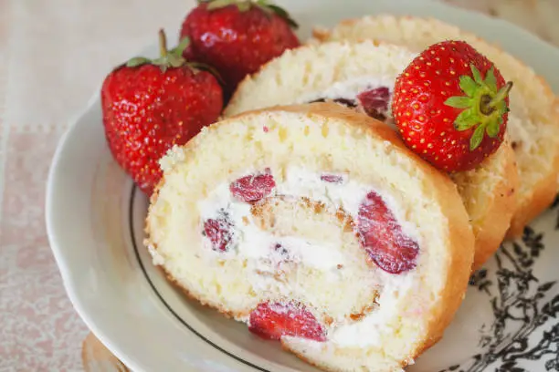 Sponge roulades with cream and fresh strawberries, close-up.