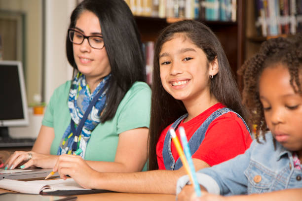 istock Teacher, mentor helps elementary-age schoolgirls with homework. 678078506