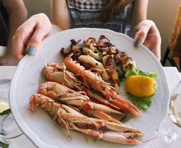 istock female hands keeping plate with shrimp 678098704