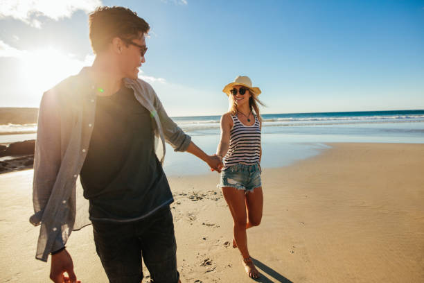 istock Romantic young couple holding hands and walking on beach 678128014