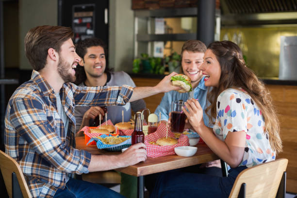 istock Young man feeding burger to friend in restaurant 678129322