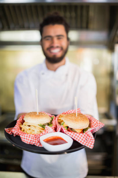 istock Chef holding burgers in plate at commercial kitchenc 678130220