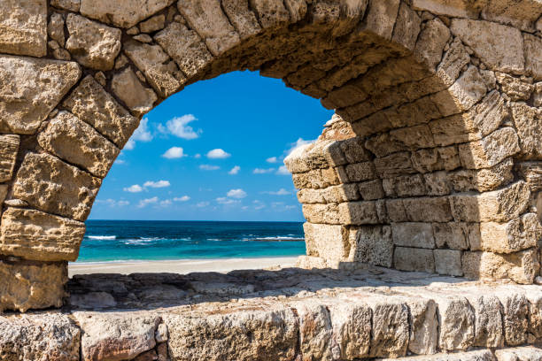 Through a semicircular stone arch of the old aqueduct is visible to the foam waves of the Mediterranean sea, which washes the shore of ancient Israel.