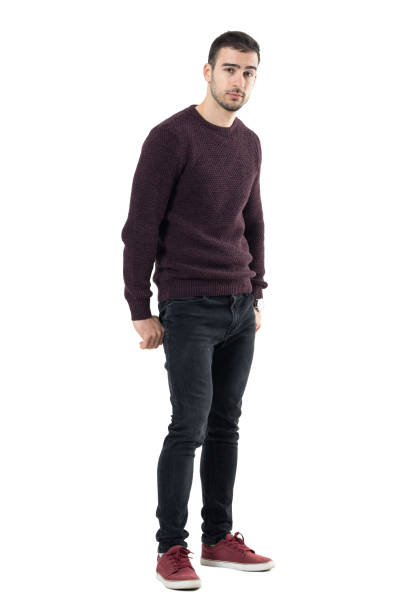 Cool seductive young casual man with hands in back pockets looking at camera