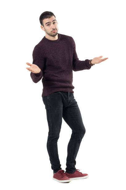 Shrugging young clueless man looking at camera with spread arms.