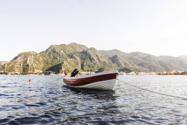 white boat near the shore in water with mountains in backround