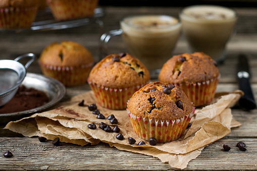 Chocolate chips muffins with coffee on wooden background