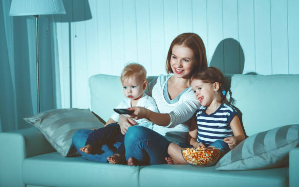 family mother and children watching television at home - family mother domestic life food imagens e fotografias de stock