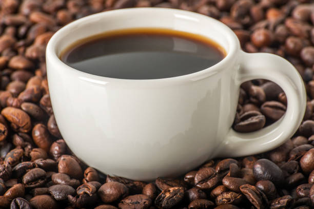 czarna kawa w białej filiżance, na tle brązowych ziaren kawy, tło kawy, aromatyczna kawa - coffee cup black coffee isolated zdjęcia i obrazy z banku zdjęć