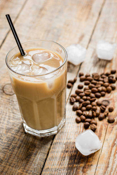 istock cold coffee glass with ice cubes on wooden table background 678211520