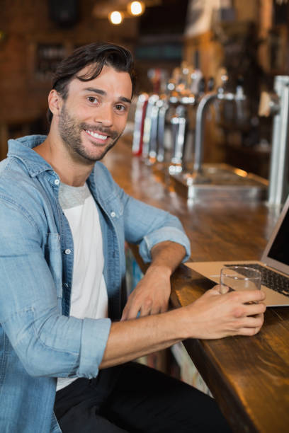 istock Young man holding beer while sitting by laptop in restarant 678217792