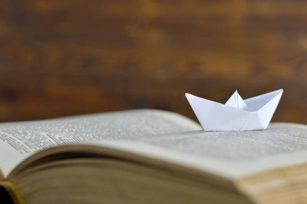 istock Paper boat on the old book 678256872