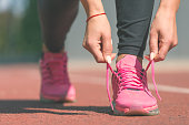 Woman tying laces of running shoes before training