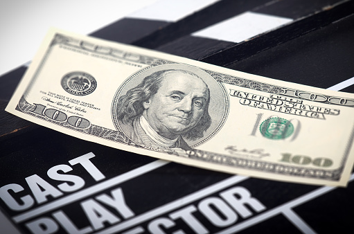 One hundred dollar bill on a movie clapper with a shallow depth of field.