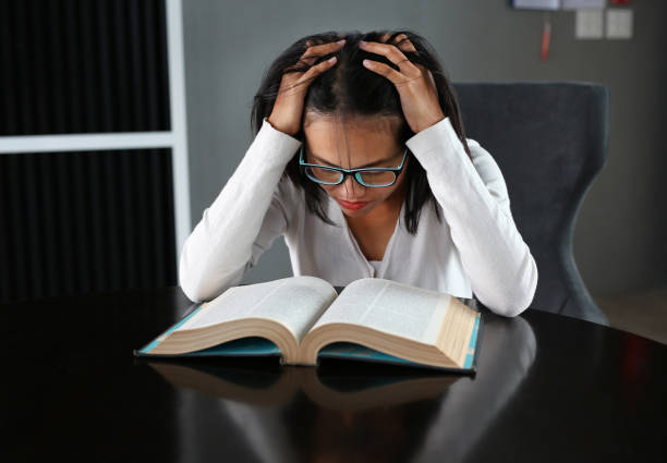 istock Asian woman under pressure reading a book in the library. 678276484