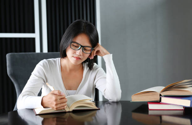 istock Asian woman reading a book in the library. 678277458