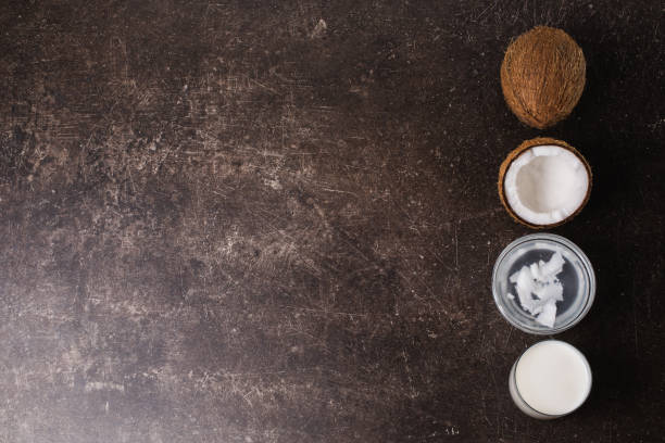 Coconut, cream, coconut milk and butter on a dark marble background. Exotic large walnut. Personal care. Spa treatments