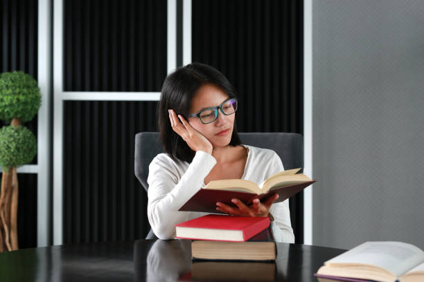 istock Asian woman reading a book in the library. 678287584