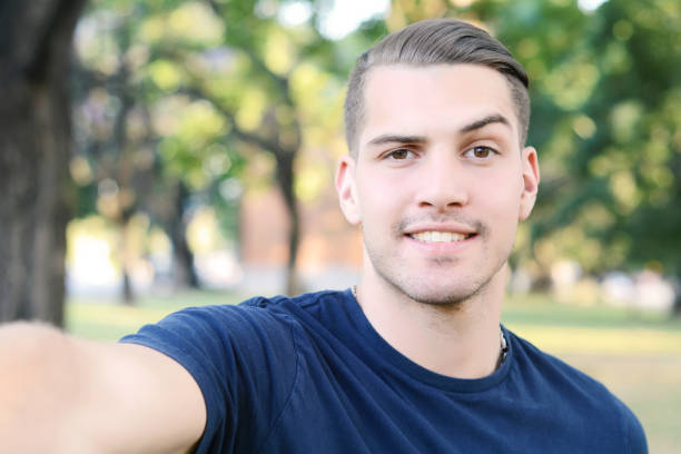 istock Young latin man taking a selfie in a park. 678294180
