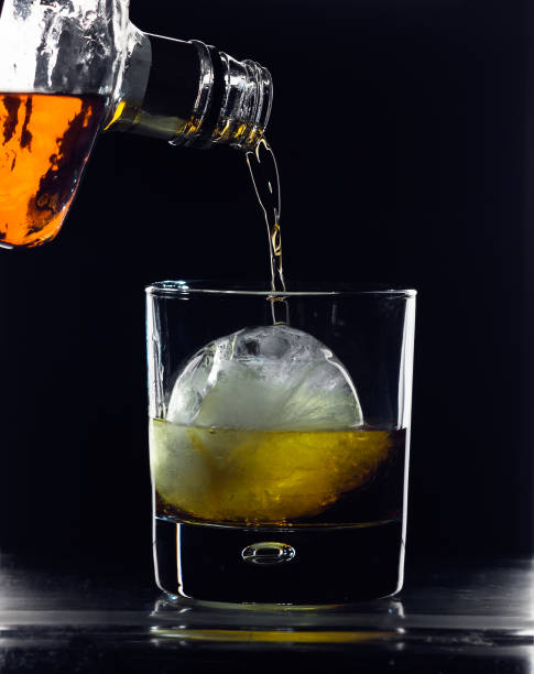 istock Alcoholic drink being poured into a glass with a round ice cube. 678305148