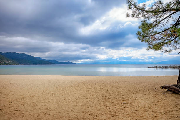 Lake Tahoe landscape photograph with dramatic clouds and a sandy beach.