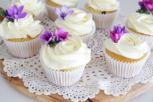 Rose flower frosting vanilla cupcakes with purple edible flowers