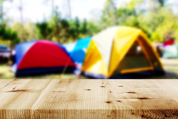 Wood table and Blurred camping and tents in forest.