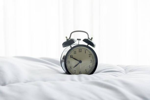 istock Alarm clock on bed in morning with sun light 678326816