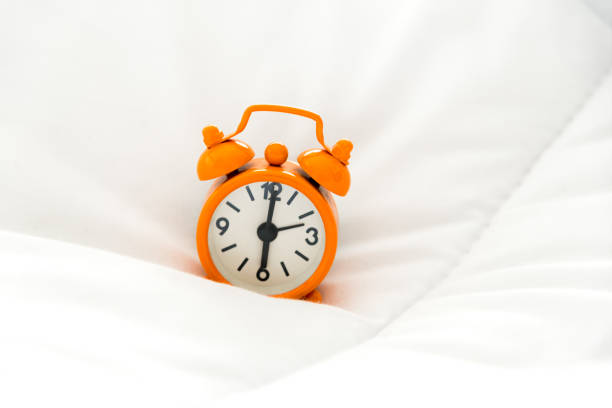 istock Alarm clock on bed in morning with sun light 678326930