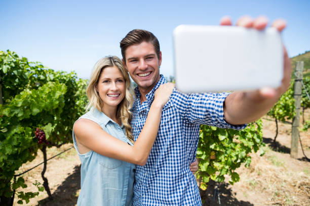 istock Happy couple taking selfie through mobile phone at vineyard 678327008
