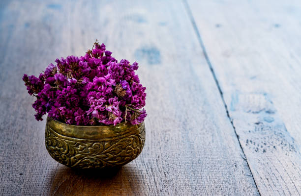 Pink flowers in old brass bowl on wooden desk