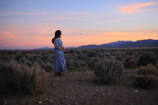 Vintage Prairie Girl in Nevada Western American Indian Cowgirl Sunset Long Hair Traditionally dressed girl in long, pale blue dress looks out over a beautiful Nevada sunset. Very old-west feel, traditional American. This is Mercy, she is an American, a mix of almost every race on the planet. The result is stunning. modest clothing stock pictures, royalty-free photos & images