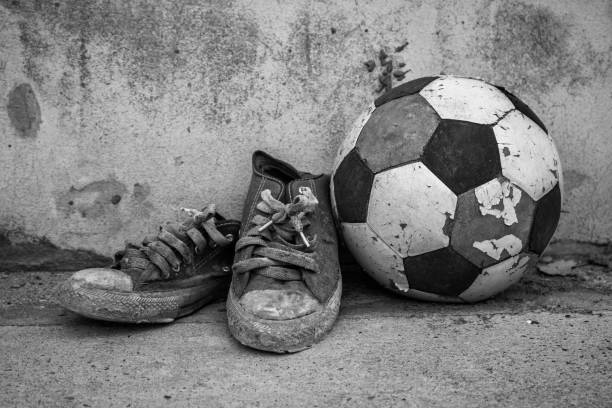 Foot of a young man on worn soccer ball