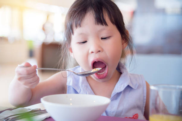 istock girl eating cereal for breakfast 678385938