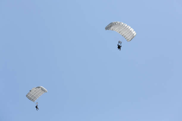 Two uniformed soldiers flying with parachutes