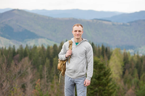 istock Male climber with brown backpack on the peak of rock 678413064