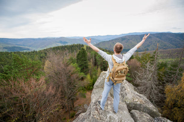 istock Male climber with brown backpack on the peak of rock 678413116