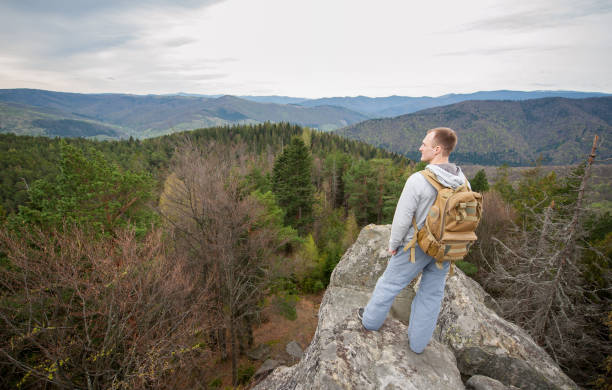istock Male climber with brown backpack on the peak of rock 678413150