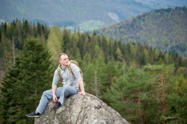 istock Male climber with brown backpack on the peak of rock 678413176
