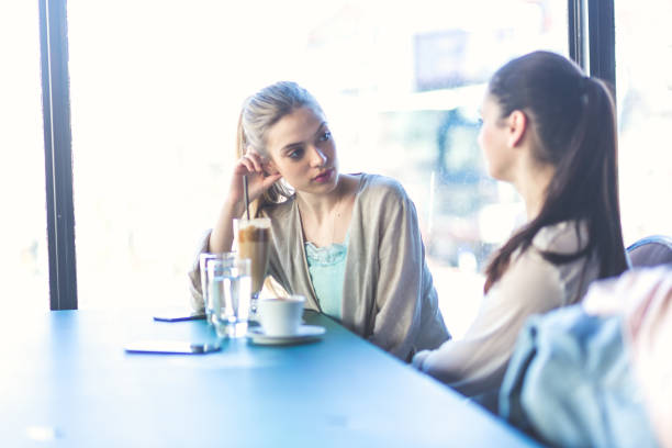 istock Young women drinking coffee and talking at cafe 678443226