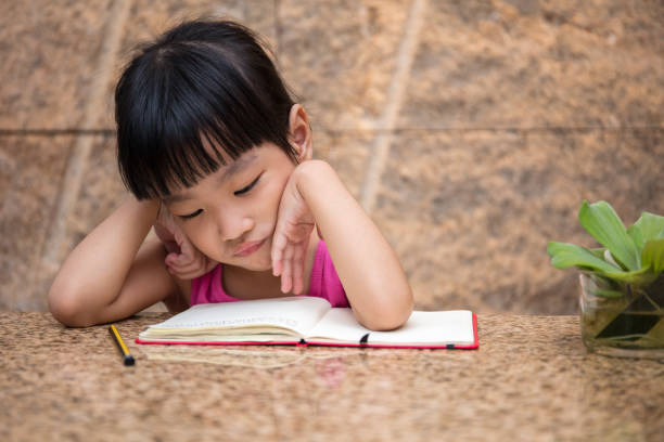 asian little chinese girl writing homework - child thinking writing little girls imagens e fotografias de stock