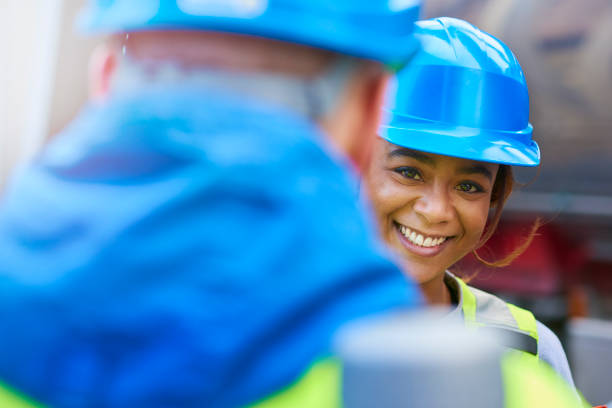 istock engineer smiles to camera as she talks to colleague 678467540