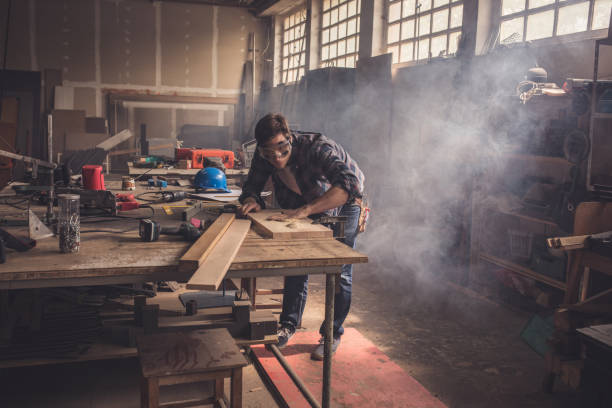 istock Male carpenter cleaning a wood from sawdust in a workshop. 678468174