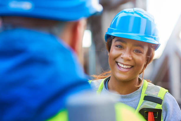 female engineer smiles to camera as she talks to colleague