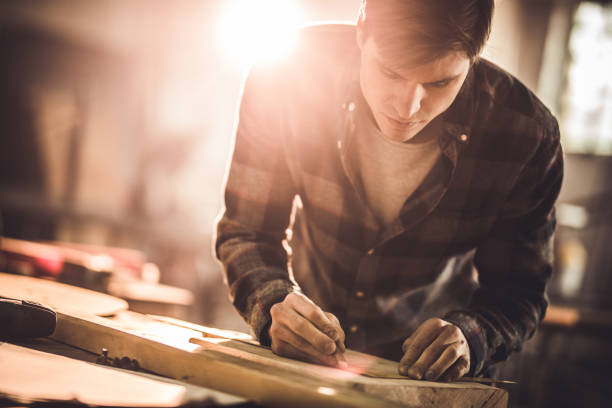 istock Young carpenter drawing measurements on a wood in a workshop. 678489670