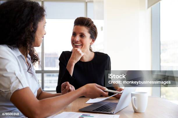 Two Businesswomen Using Laptop Computer In Office Meeting Stock Photo - Download Image Now