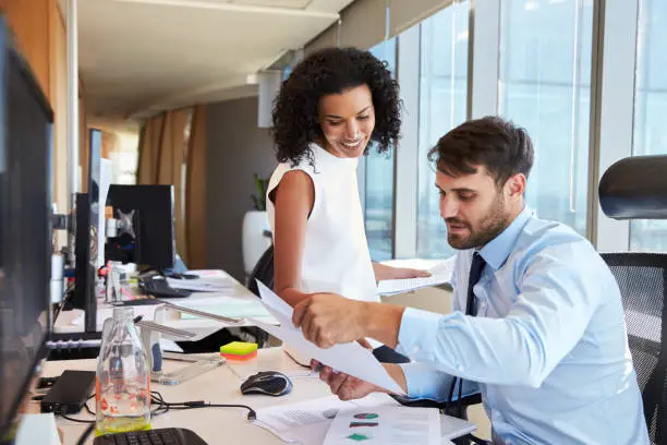 Photo of Businesspeople Working At Office Desk On Computer Together