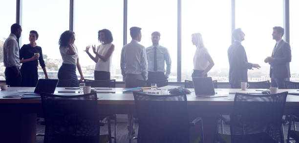 Businesspeople Stand And Chat Before Meeting In Boardroom Businesspeople Stand And Chat Before Meeting In Boardroom wide screen photos stock pictures, royalty-free photos & images
